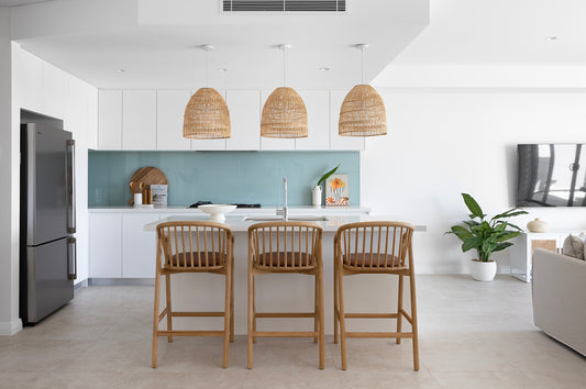 Three Elliston handmade pendant lights hang over a white island bench. The kitchen has a calming and practical light blue glass backsplash. Perfect for a modeern coastal Australian home.