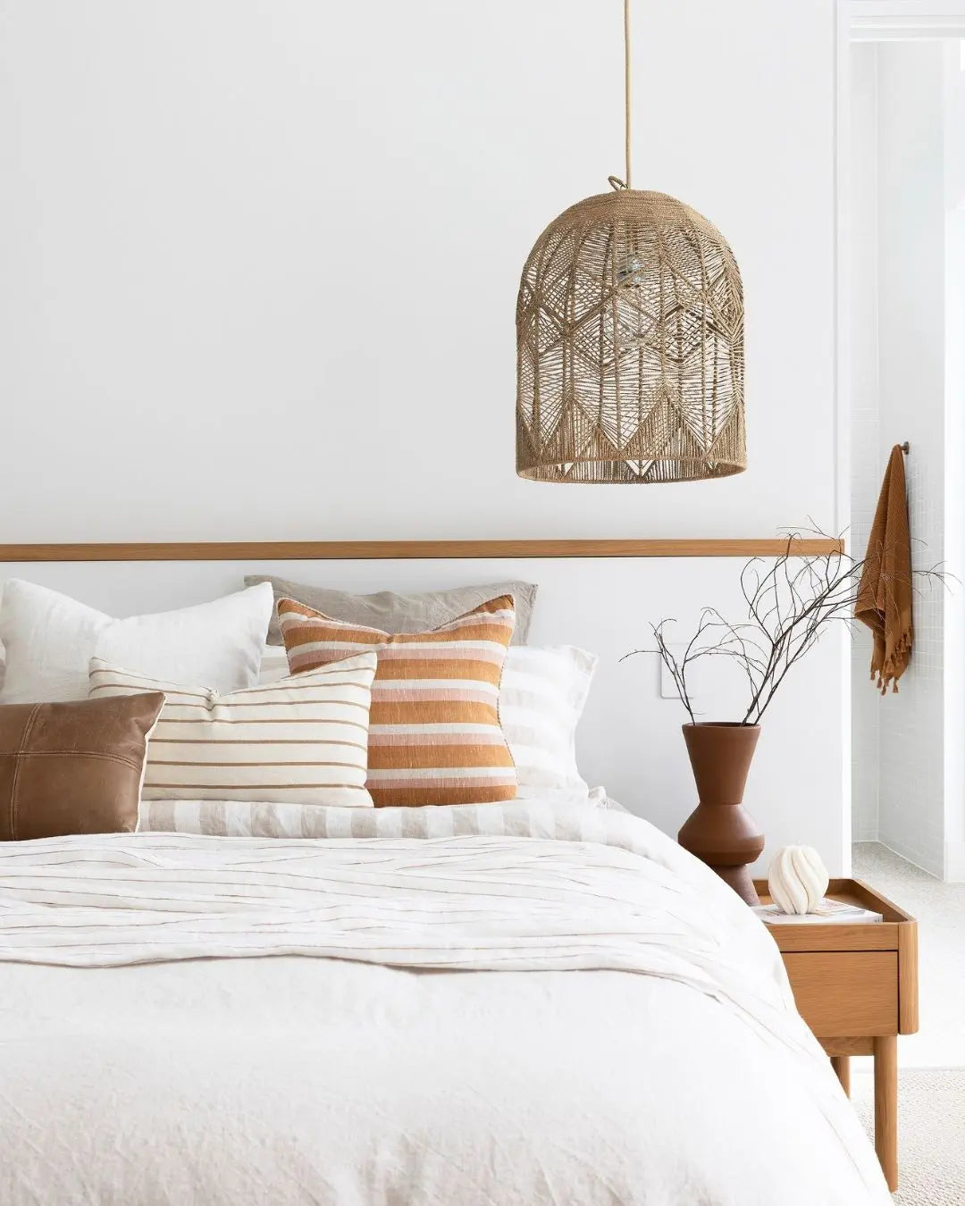 seagrass pendant light in natural colour used as a bedise pendant over a gorgeous bed made with natural linen doona cover and sheets and terracotta and beige coloured cushions.