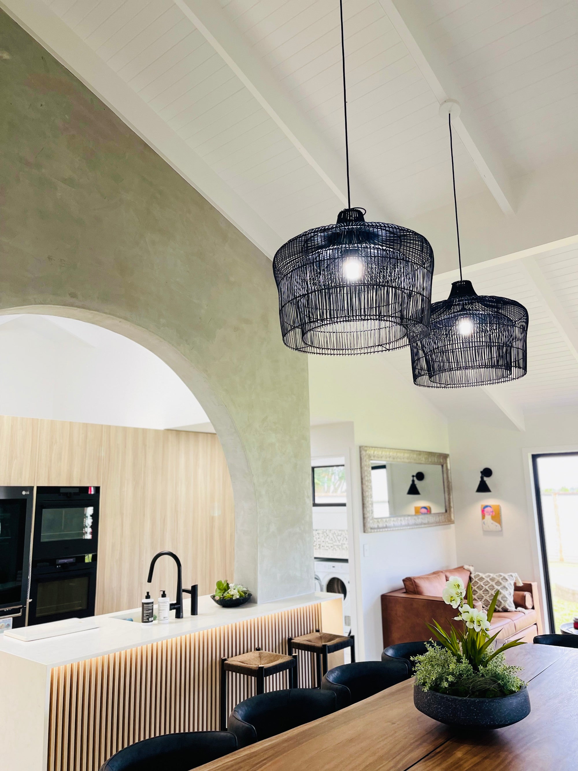 Two large Henley black sustainable pendant lights hanging above a timber dining table.