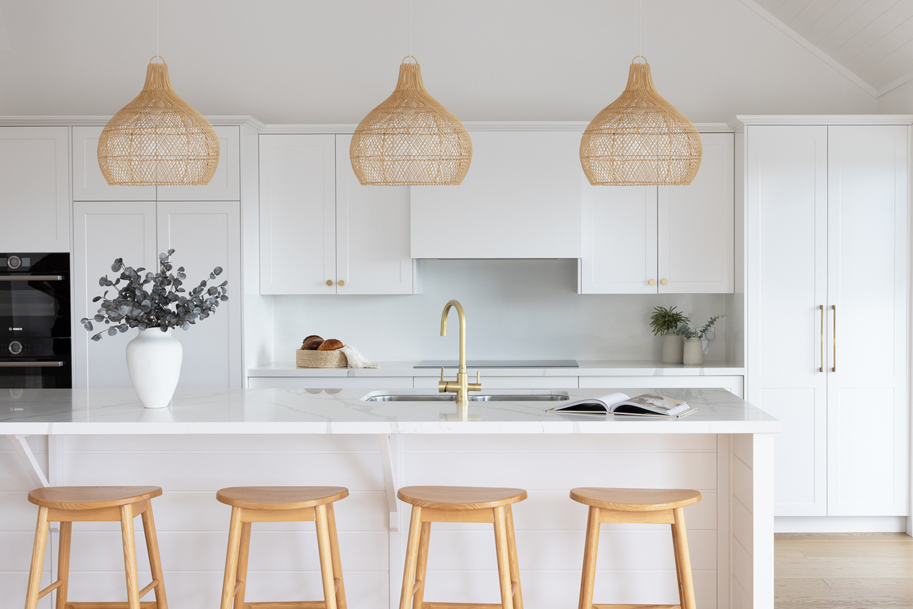 Natural rattan pendant lights over a coastal style kitchen bench