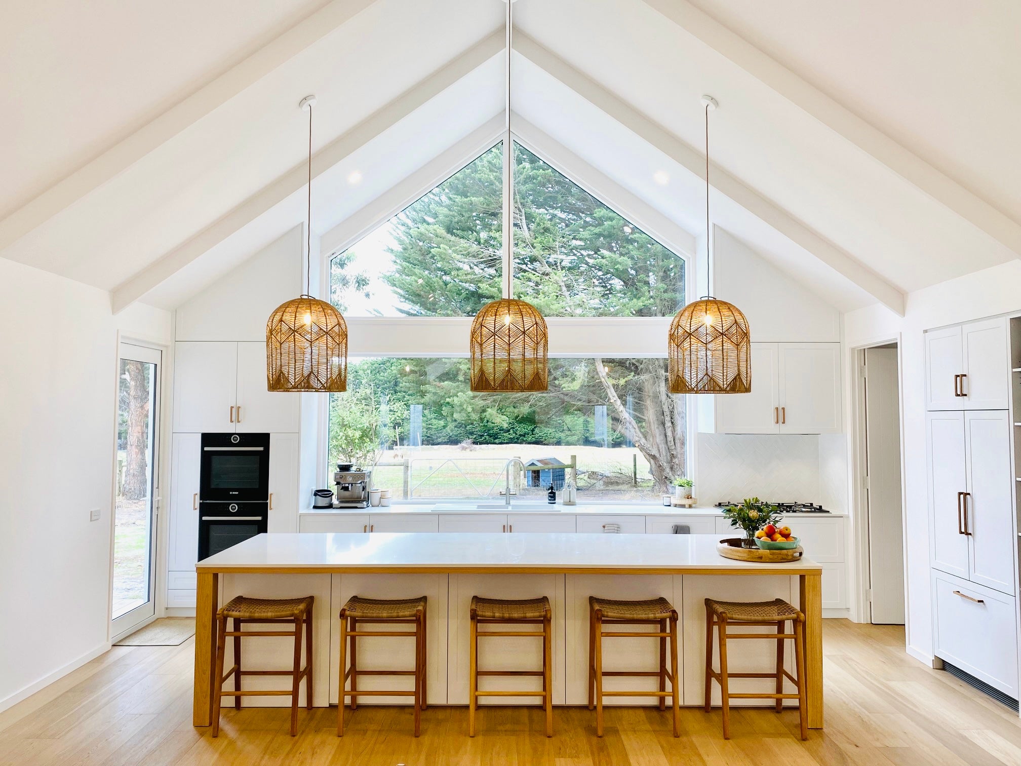 Three Airlie large natural kitchen feature lights hang above a large kitchen island bench.