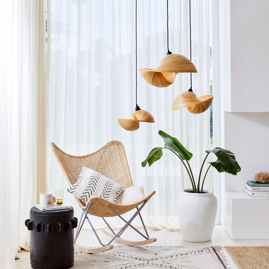 A cluster of Esperance natural feature lighting hang in a reading well-lit reading nook. There is a timber rocking chair, black stool and large plant in the living space.