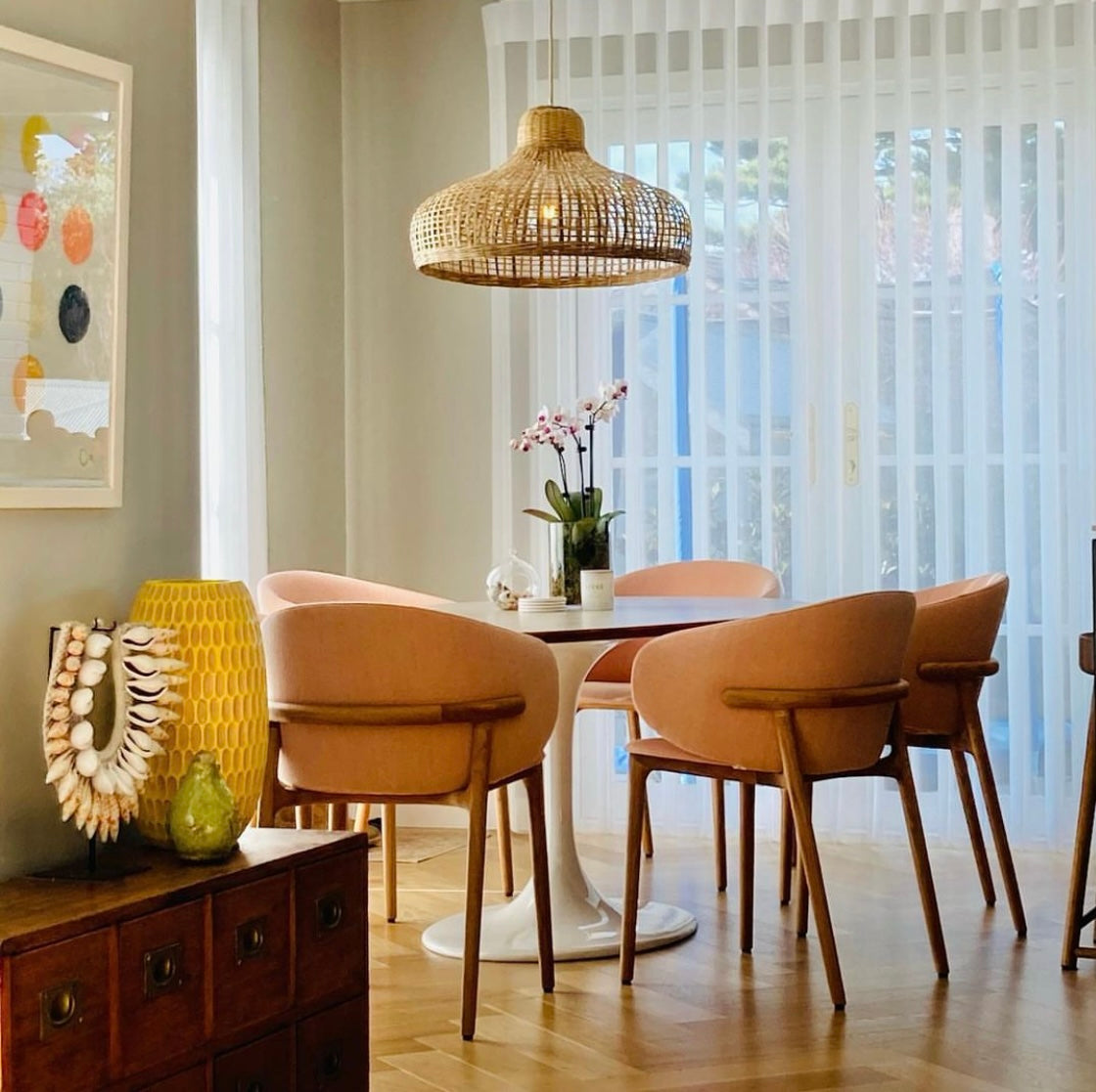 A single Portsea sustainable pendant light in a natural colour hangs above a circular modern dining table.