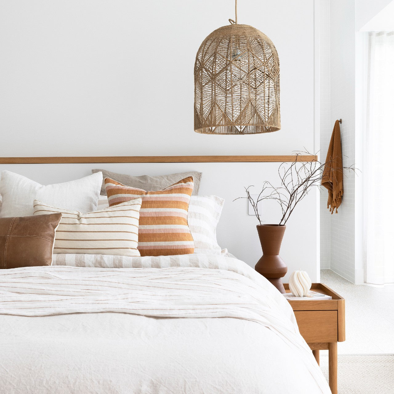 seagrass pendant light in natural colour used as a bedise pendant over a gorgeous bed made with natural linen doona cover and sheets and terracotta and beige coloured cushions.