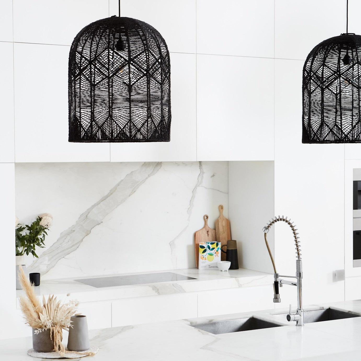 two large seagrass pendant light shades are hung over a luxurious white marble kitchen bench