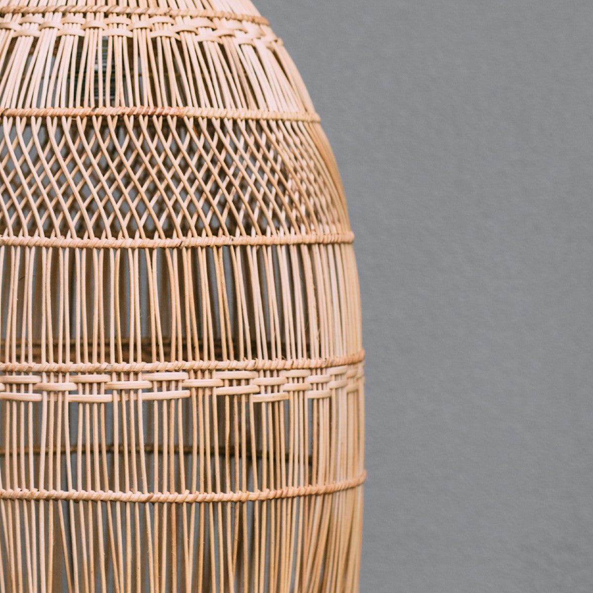 rattan boho light. rattan pendant lighting. close up photo shows the detail in the weave with a mixture of straight lines and a criss cross pattern