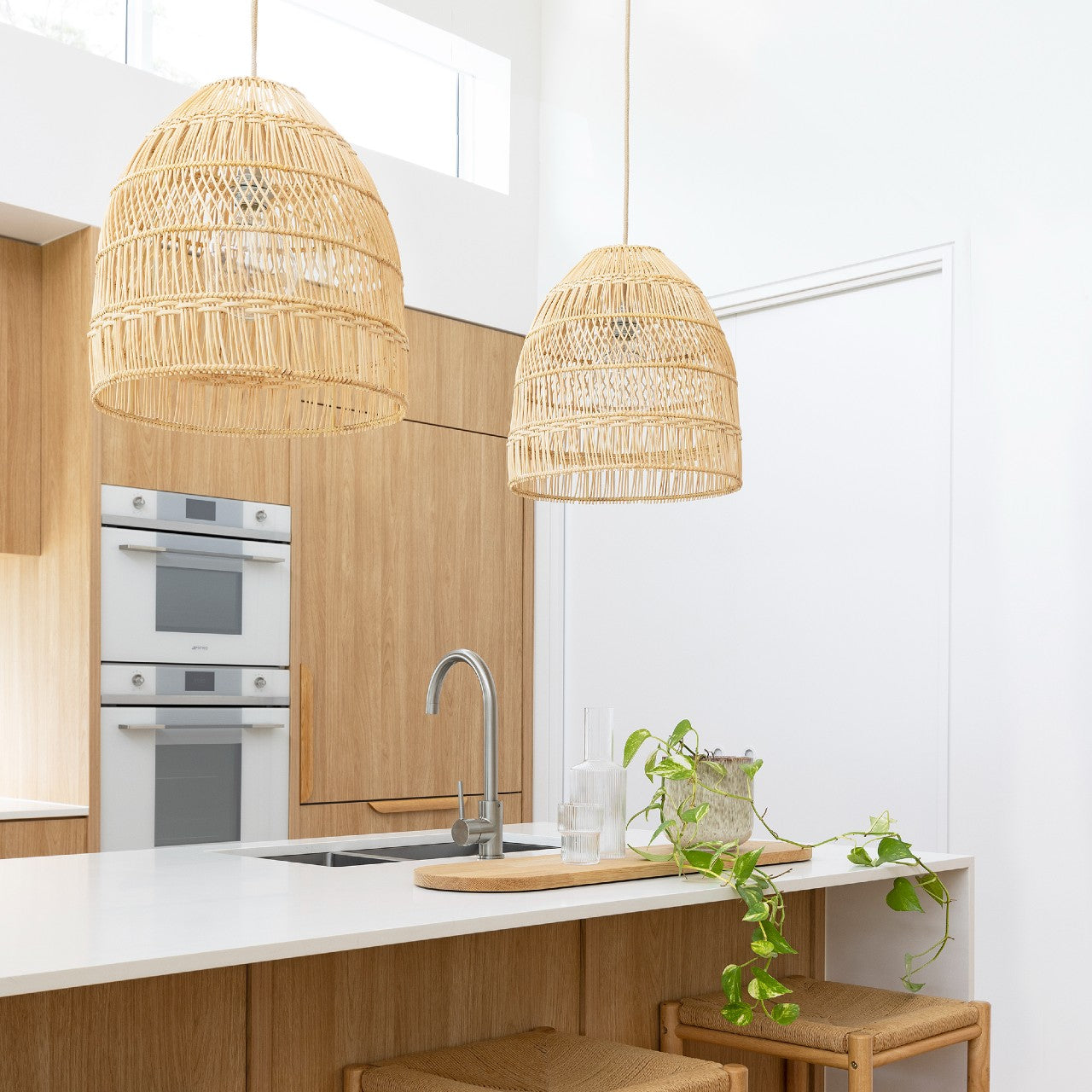 Coastal style pendant lights hanging above a light and bright timber and white kitchen.