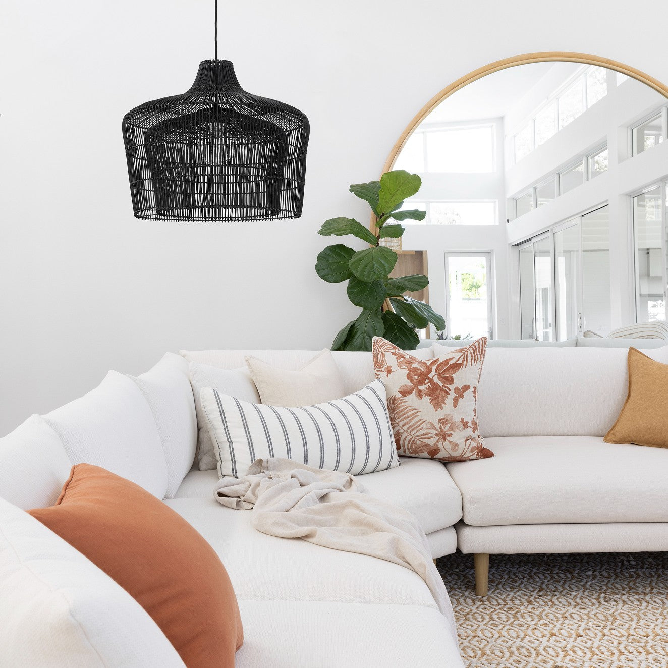Large rattan pendant light Australia. Black doubel caged rattan pendant in light, white lounge room with over sized round rattan mirror, and comfortable couch. ra
