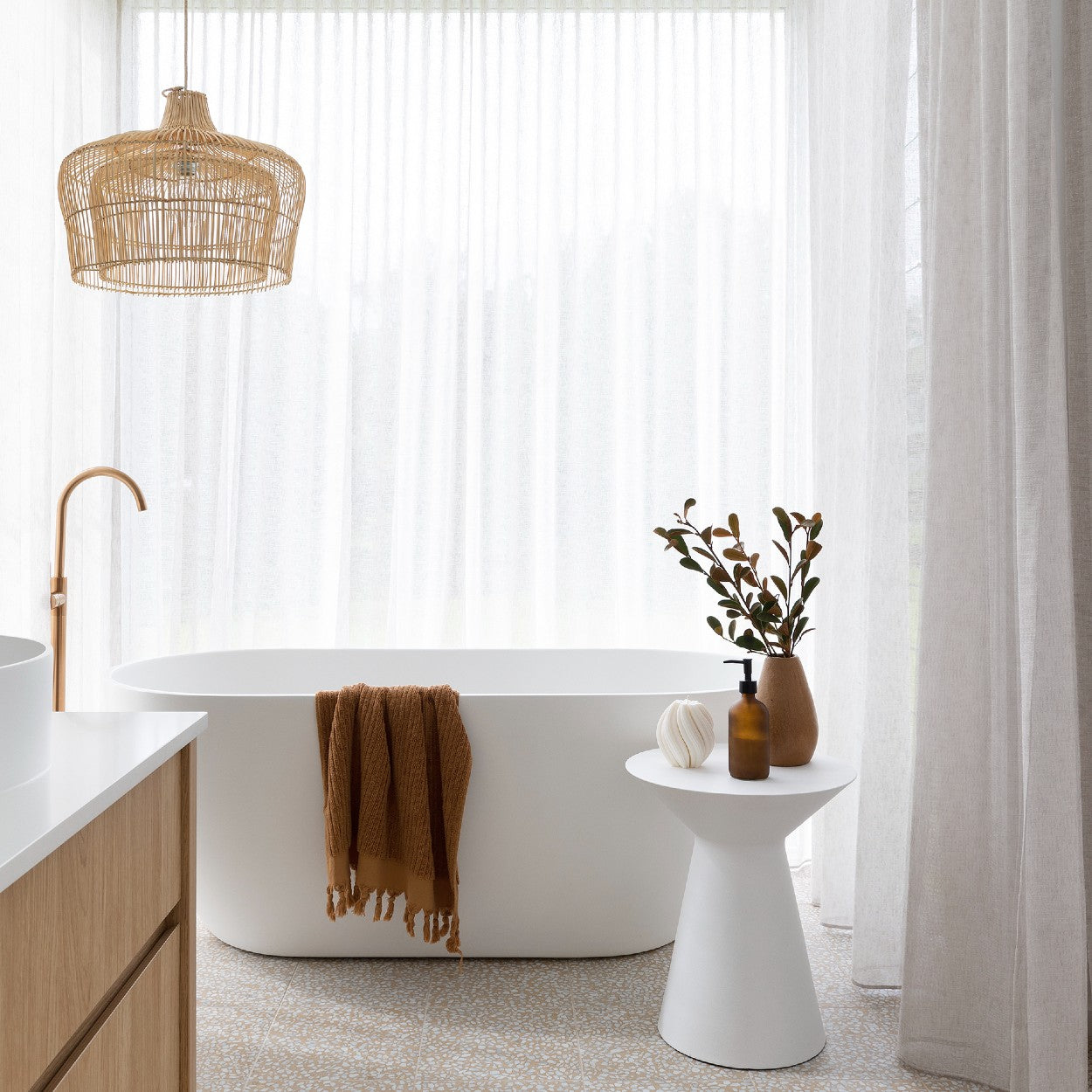 Rattan pendant light buy online Australia. Double caged rattan pendant hanging above a large white free standing bath surrounded by floor to ceiling sheer linen curtains.